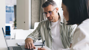 Business coach helping client in the office while both looking at laptop