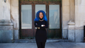 woman with blue hair and arms crossed smiling for photo